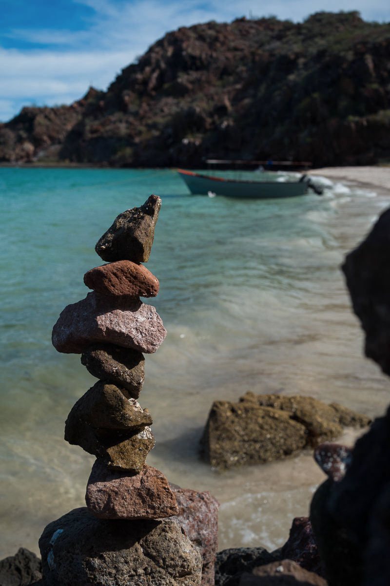 Travel photography: balanced stones on a beach with turquoise water, in WorthWait's Original film
