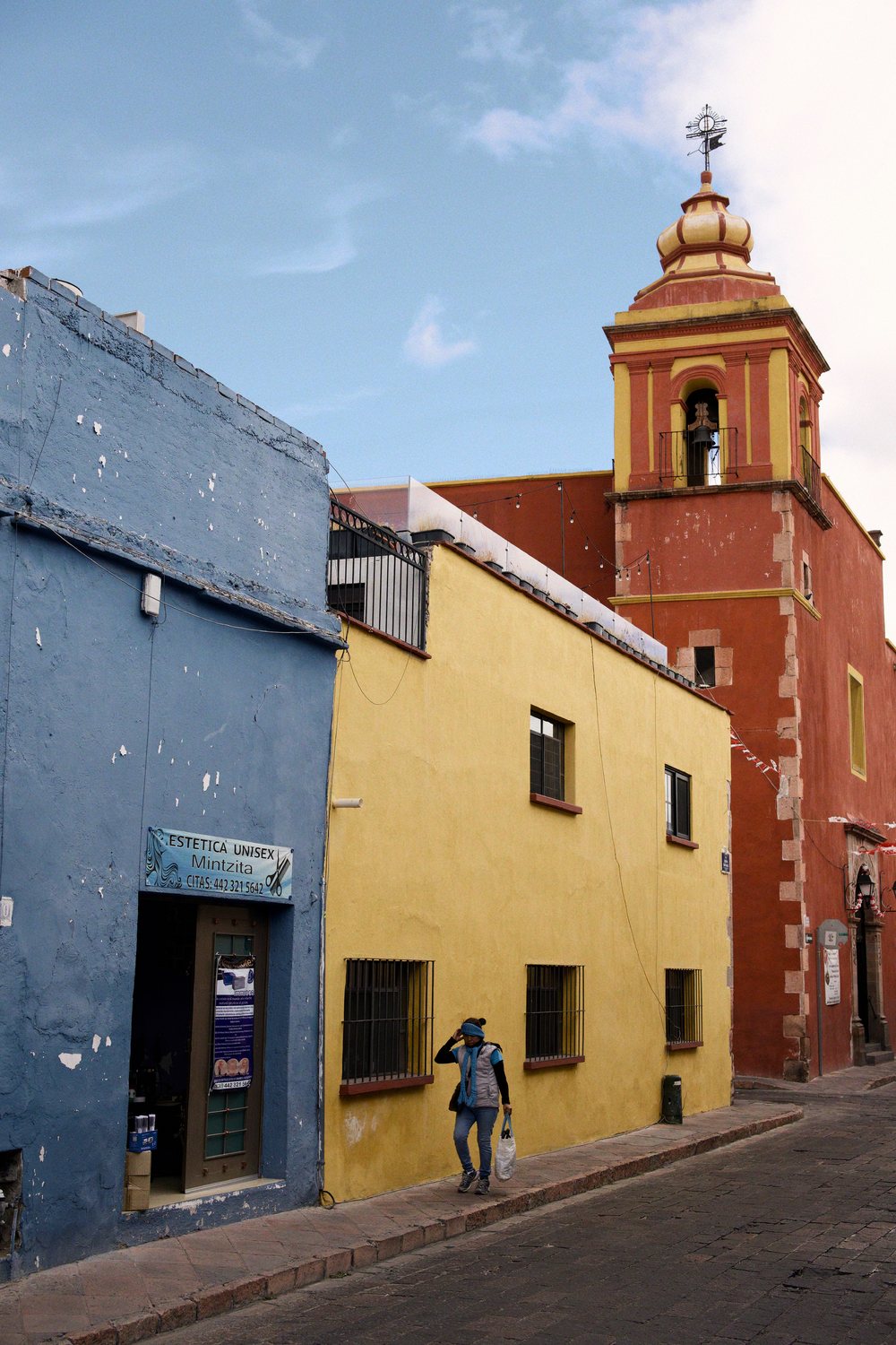 Street photography: colonial houses in blue, yellow and red with a church tower, in WorthWait's Negative film