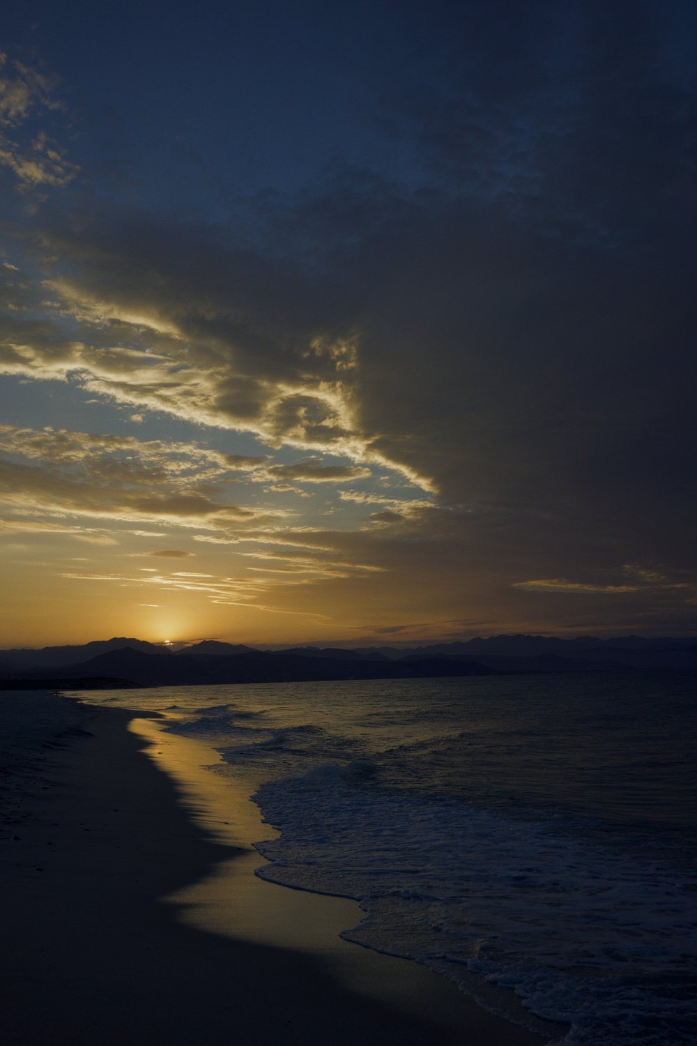 Travel photography: a shoreline at sunset under golden clouds, in WorthWait's Flat film